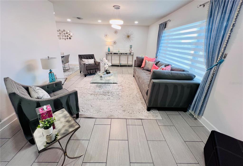 A living room features gray tile flooring, a large sofa, two armchairs, and a rug — 13607 101ST TERRACE, SEMINOLE, FL