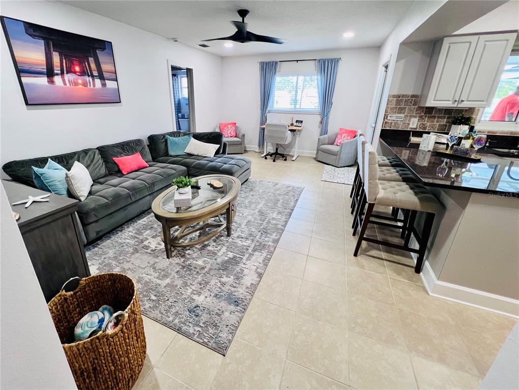 A living room with a gray sectional, area rug, and breakfast bar kitchen area — 13607 101ST TERRACE, SEMINOLE, FL