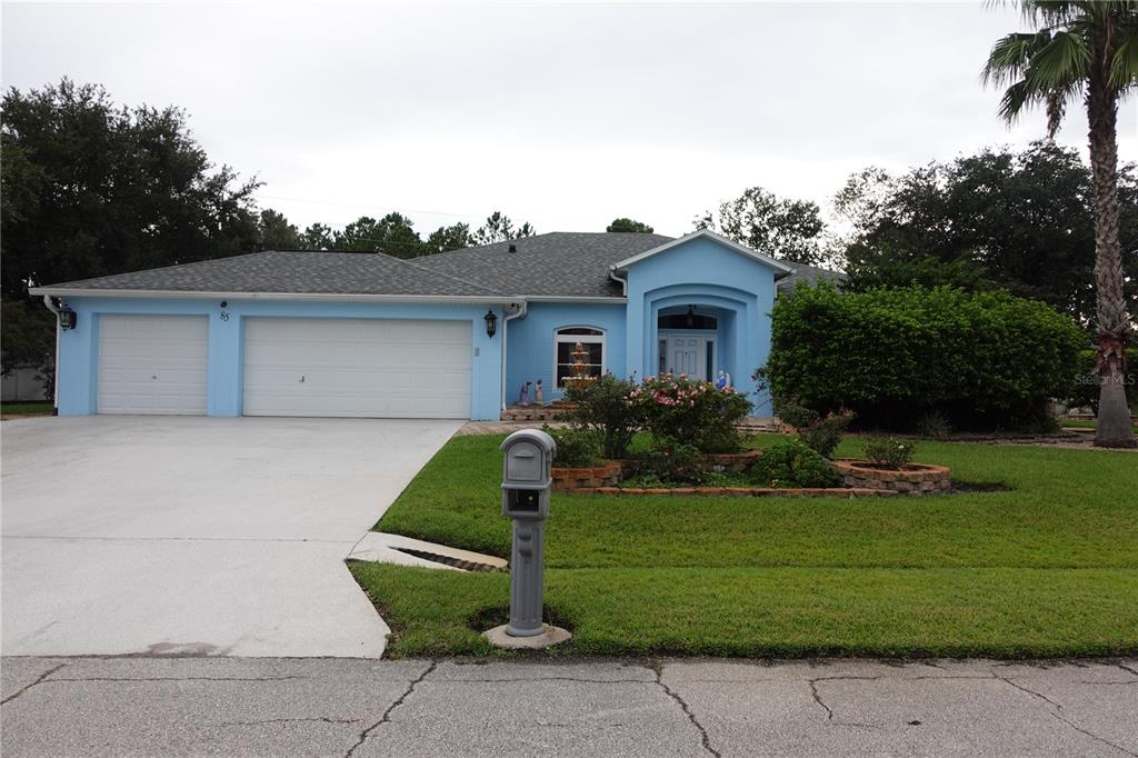 A light blue single-story house with a three-car garage and a front yard — 85 LANCELOT DRIVE, PALM COAST, FL