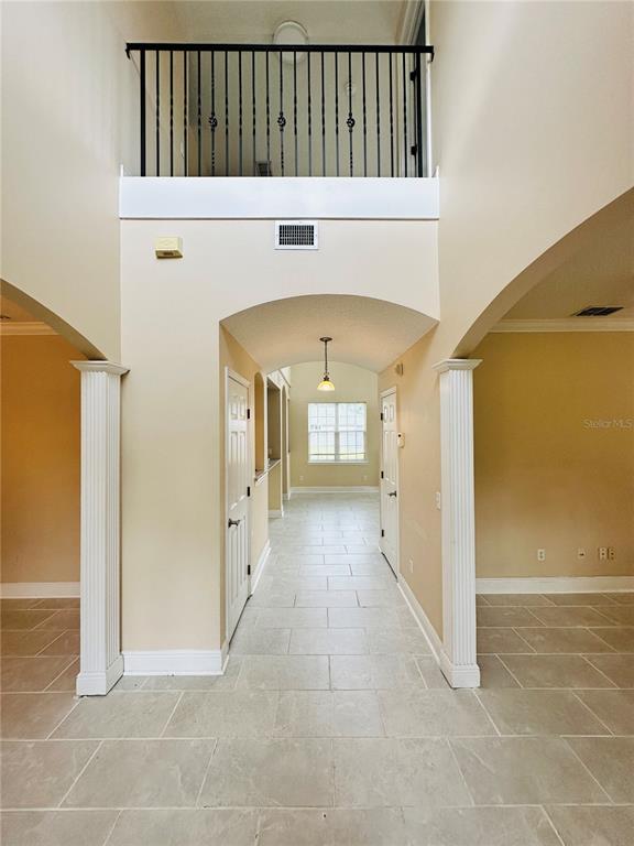 A tiled hallway leads through an arched opening toward a window in a two-story home — 438 PALM DRIVE, SANFORD, FL