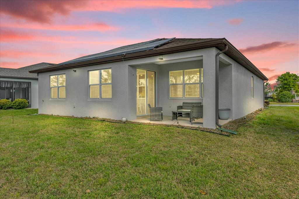A gray house exterior features a dark front door, a garage, and a small garden — 9491 SW 52ND LOOP, OCALA, FL