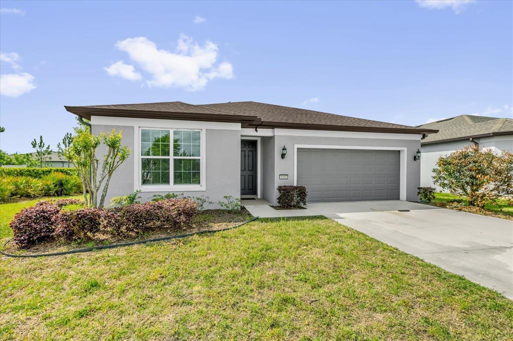 A single-story house with a gray stucco exterior, a two-car garage, and a front lawn — 9491 SW 52ND LOOP, OCALA, FL