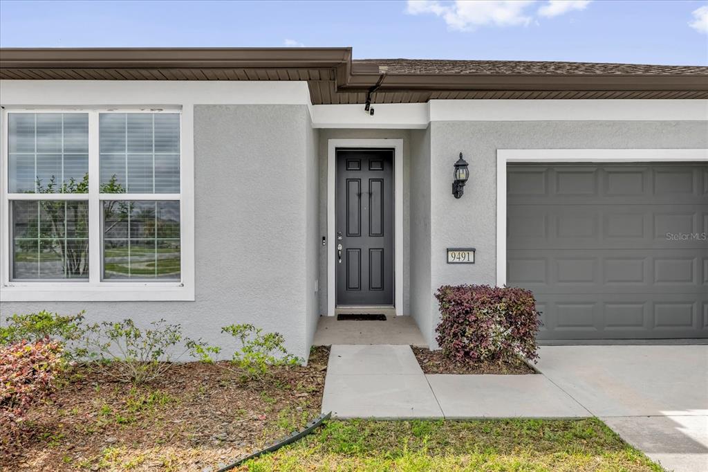 A bedroom features a bed, two side tables, a ceiling fan, and a large window — 9491 SW 52ND LOOP, OCALA, FL