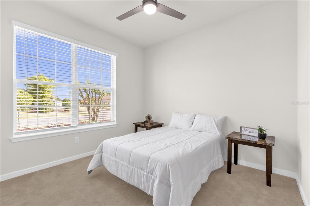 A bedroom features a white bed, a closet with sliding doors, and an open doorway — 9491 SW 52ND LOOP, OCALA, FL