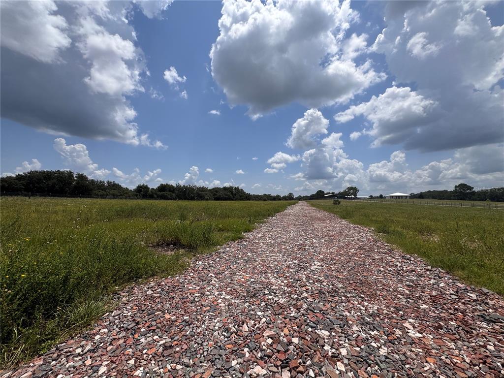 A gravel driveway leads through a grassy field under a cloudy blue sky — 4557 GLEN SAINT MARY ROAD, LAKE WALES, FL