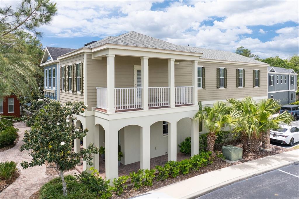 An exterior view of a two-story house with a covered balcony and ground-level patio — 208 CUTLASS WAY, OLDSMAR, FL