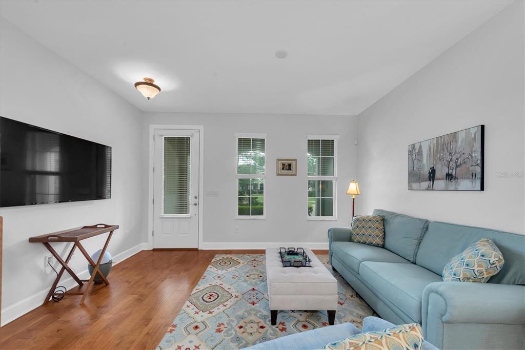 A living room features light gray walls, hardwood floors, a blue sofa, and a television — 208 CUTLASS WAY, OLDSMAR, FL