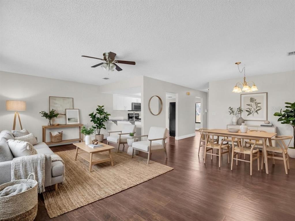 A living and dining area with wood-look flooring, a ceiling fan, and neutral furniture — 1801 E LAKE ROAD UNIT 20C, PALM HARBOR, FL