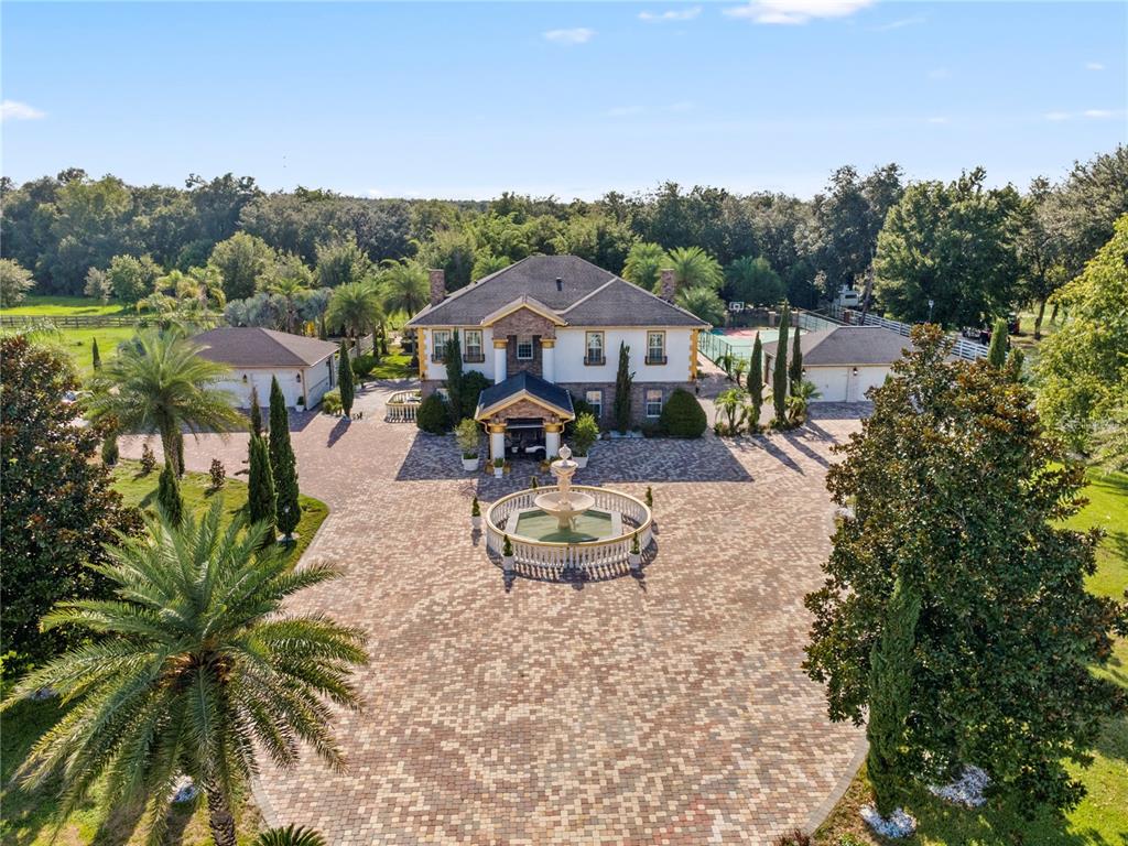 An aerial view shows a large house with a circular fountain in a paved courtyard — 34417 DONNA VISTA PLACE, EUSTIS, FL