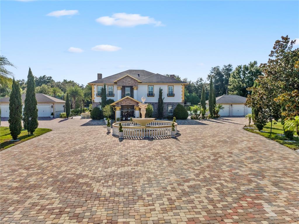 A large two-story house with a circular fountain in a paved driveway between two garages — 34417 DONNA VISTA PLACE, EUSTIS, FL