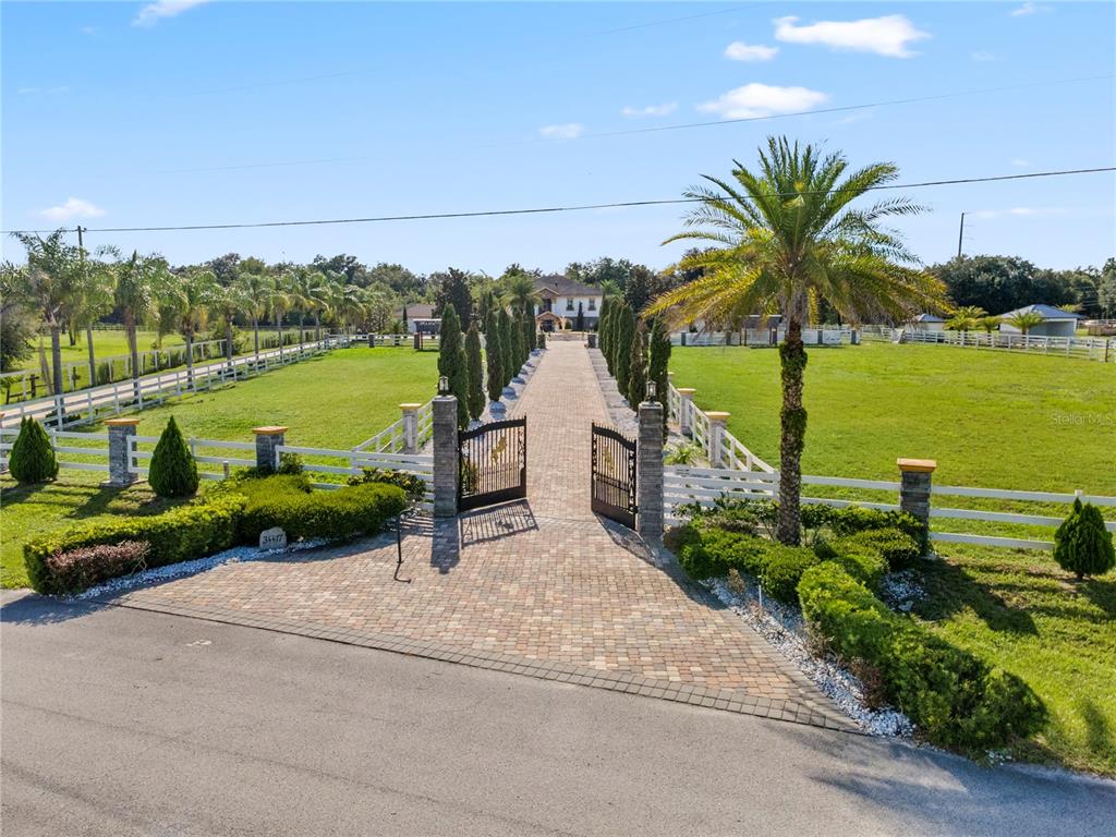 A long brick driveway leads through an open gate to a house on a grassy lot — 34417 DONNA VISTA PLACE, EUSTIS, FL