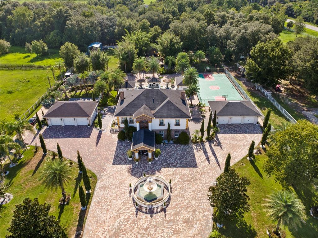 An aerial view shows a large house with a fountain, two garages, and a basketball court — 34417 DONNA VISTA PLACE, EUSTIS, FL