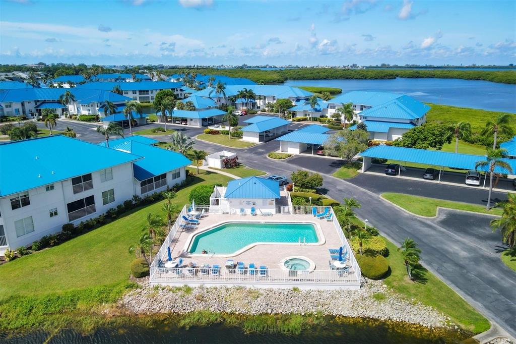 An aerial view shows a swimming pool and hot tub surrounded by residential buildings — 879 AUDUBON DRIVE UNIT 879, BRADENTON, FL