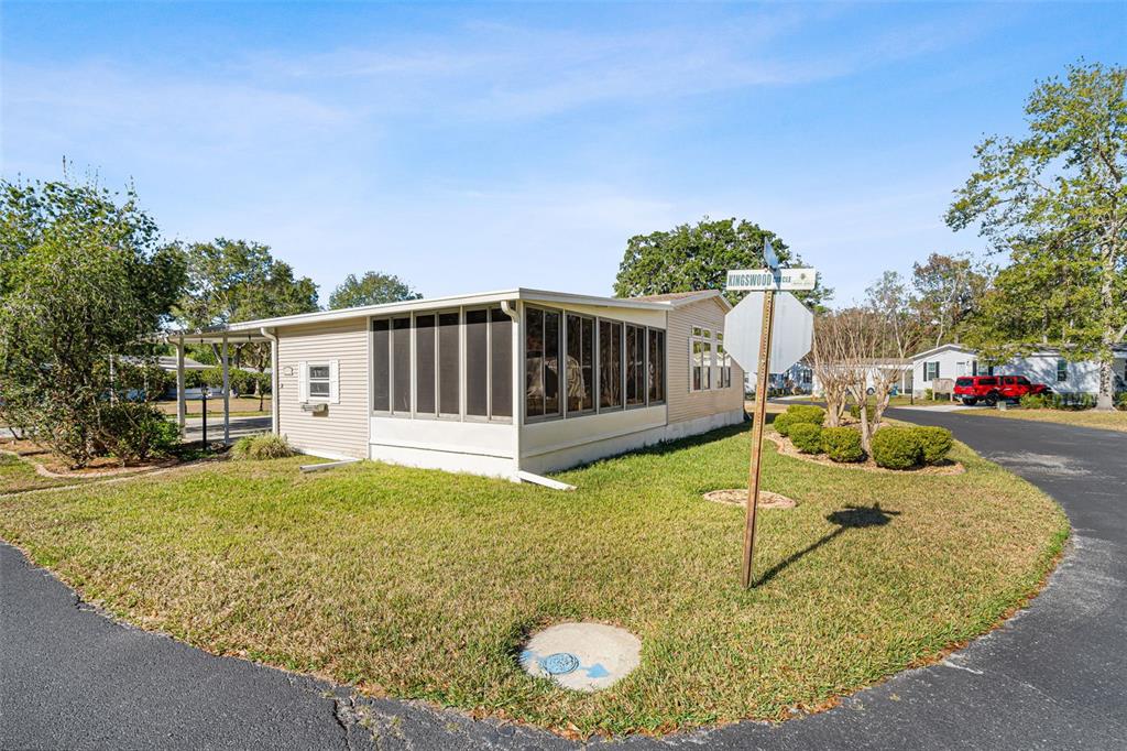 A single-story manufactured home with a screened-in porch sits on a corner lot — 2973 KINGSWOOD CIRCLE, BROOKSVILLE, FL