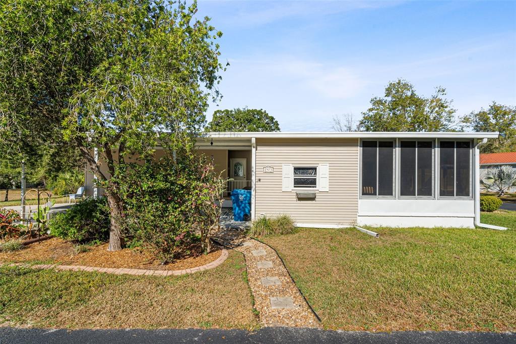 A single-story house with beige siding, a screened-in porch, and a stone walkway — 2973 KINGSWOOD CIRCLE, BROOKSVILLE, FL