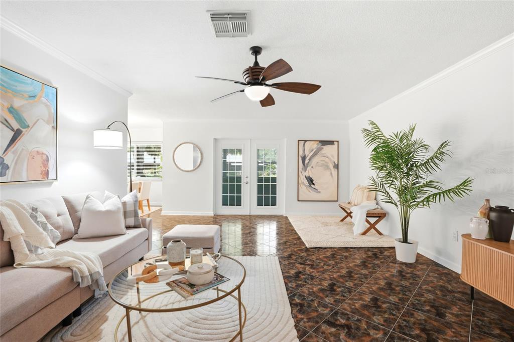 A living room features a beige sofa, glass coffee table, and dark patterned tile flooring — 1208 14TH CIRCLE SE, LARGO, FL