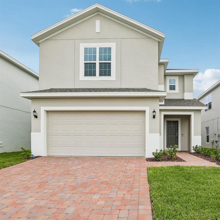 A modern kitchen features white cabinetry, a large gray island countertop, and stainless steel appliances — 1349 SAWGRASS HAMMOCK LANE, DAVENPORT, FL