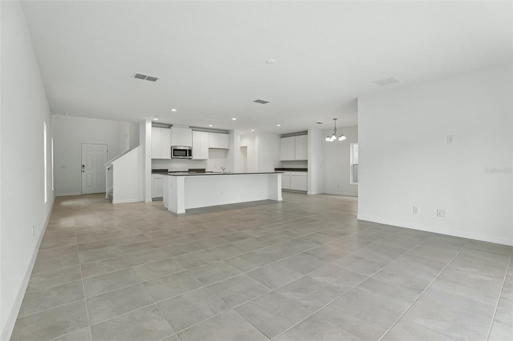 A kitchen area features white cabinets, dark countertops, and tile flooring next to a dining space — 1349 SAWGRASS HAMMOCK LANE, DAVENPORT, FL