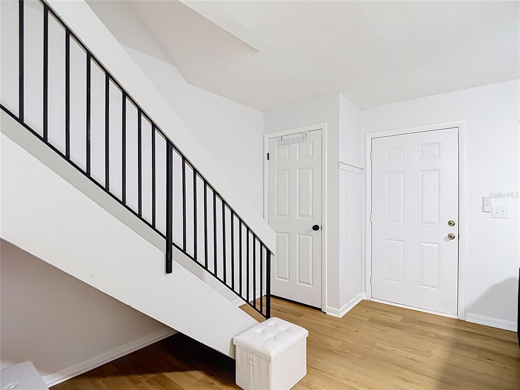 An interior view shows a staircase with a black metal railing, two white doors, and wood-look flooring — 14732 PINE GLEN CIRCLE, LUTZ, FL