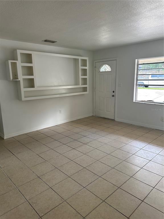 A room with light-colored tile flooring, white walls, a built-in wall unit, and a front door — 651 LORRAINE CIRCLE, LAKE WALES, FL