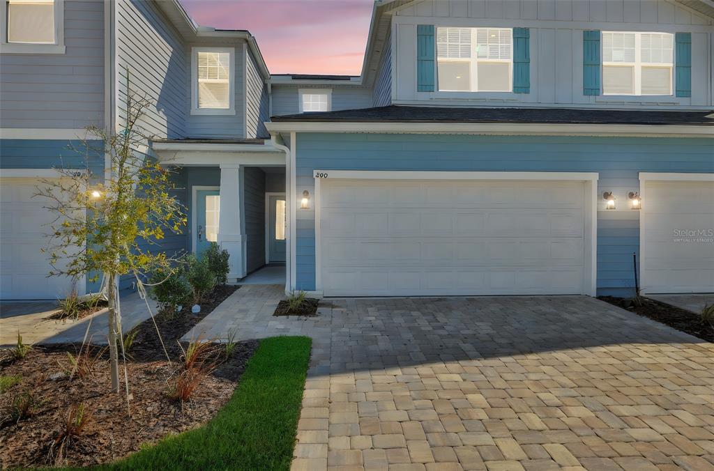 A two-story townhouse exterior features blue siding, a paved driveway, and a two-car garage — 357 WOODS LANE, ST AUGUSTINE, FL