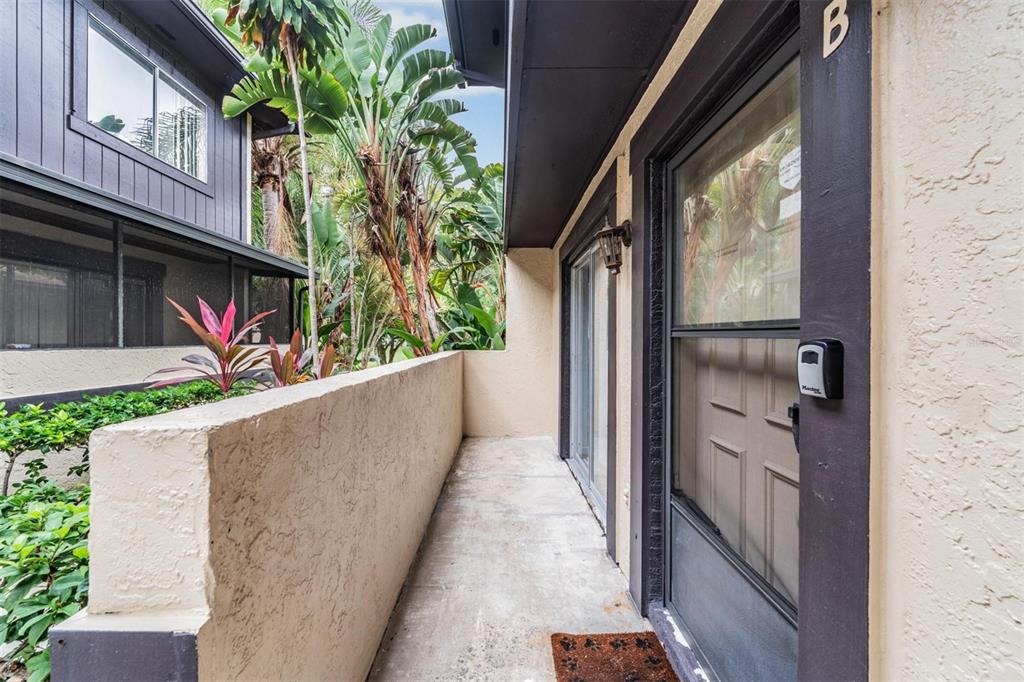 An exterior view of a concrete balcony with a door and a low stucco wall — 2936 LICHEN LANE UNIT B, CLEARWATER, FL