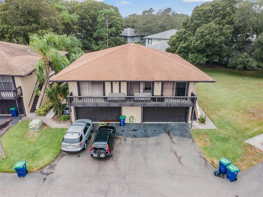 An elevated two-story residential building with a brown roof, balcony, and ground-level garage doors — 2936 LICHEN LANE UNIT B, CLEARWATER, FL