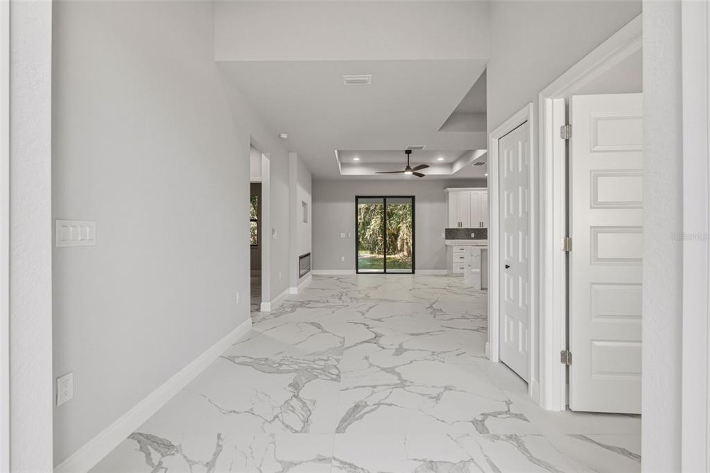 A view through a doorway into a living area with white marble-patterned tile flooring — 3466 LANAI, NORTH PORT, FL