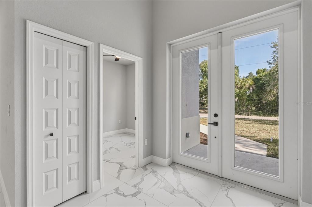 An entryway features white marble-look tile flooring, a closet, a doorway, and double glass doors — 3466 LANAI, NORTH PORT, FL
