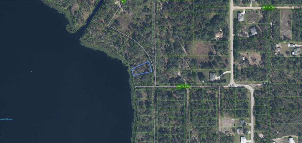 This aerial map shows a vacant residential lot highlighted in blue along a lakefront — 6407 E BANYAN PLACE, SEBRING, FL