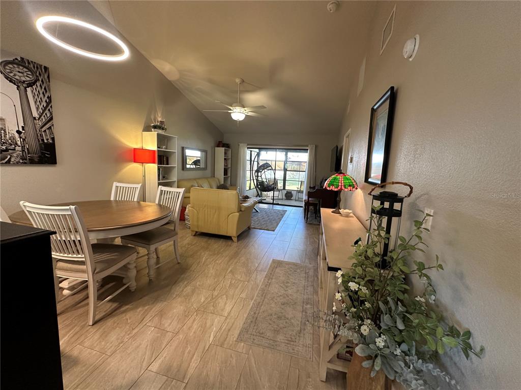 A living room features a vaulted ceiling, light-colored tile flooring, and a beige leather sofa — 5480 BRASSY LOOP, NORTH PORT, FL