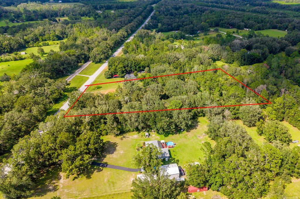An aerial view shows a wooded lot outlined in red next to a residential property — 5301 NW COUNTY ROAD 235, ALACHUA, FL