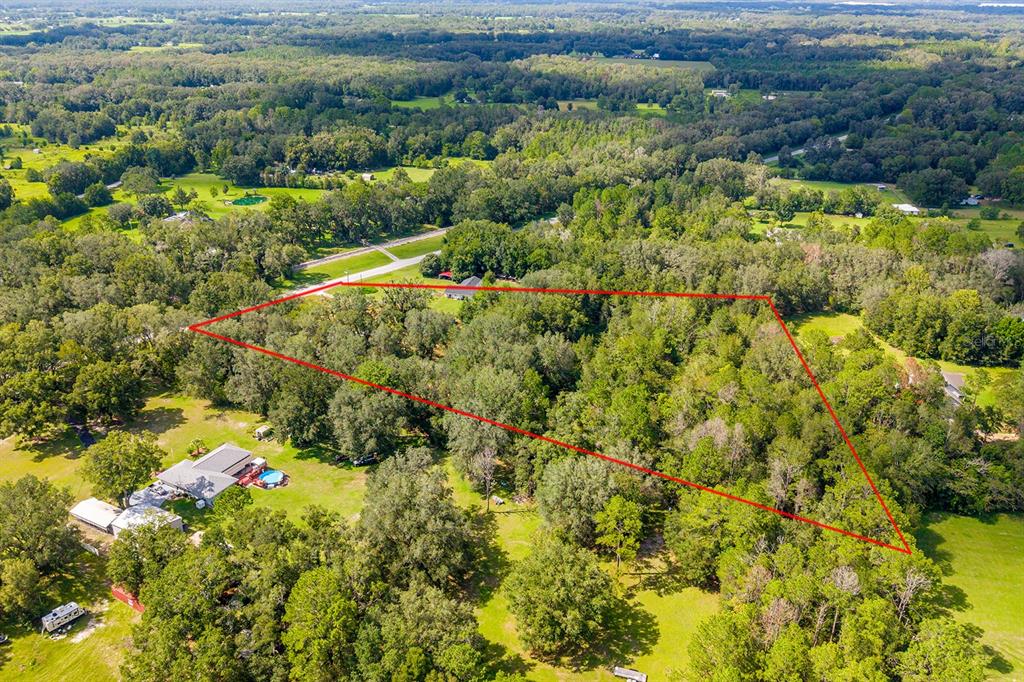 An aerial view shows a wooded lot outlined in red next to a residential property — 5301 NW COUNTY ROAD 235, ALACHUA, FL