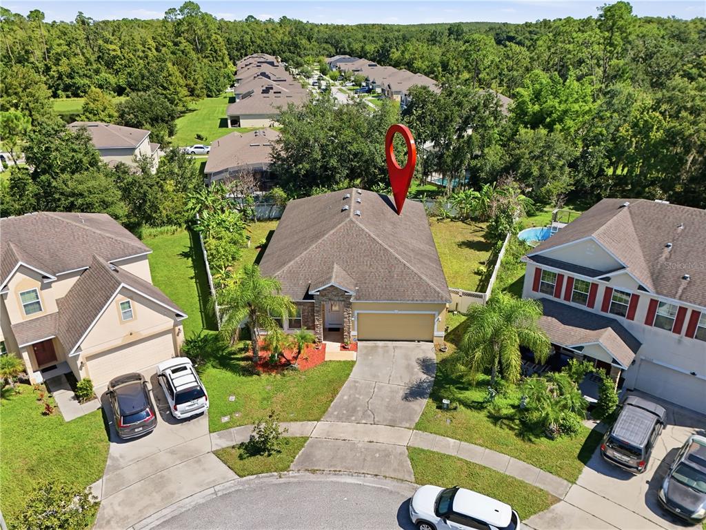 An aerial view shows a single-story house with a tan exterior and a red map pin — 2803 MOONSTONE BEND, KISSIMMEE, FL