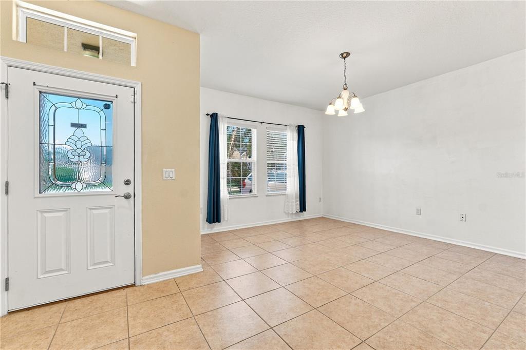 An entryway leads into a dining area with tile flooring, a chandelier, and two windows — 2803 MOONSTONE BEND, KISSIMMEE, FL