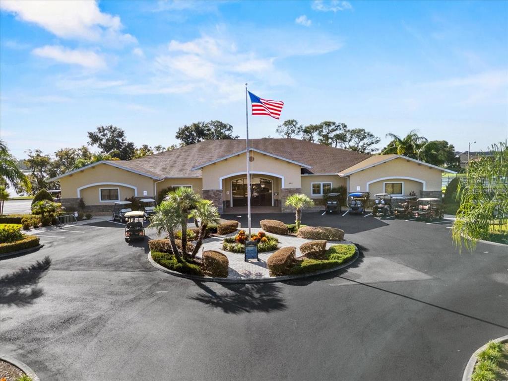 An exterior view of a single-story community building with a circular driveway and golf carts — 114 LAYNEWADE ROAD, POLK CITY, FL