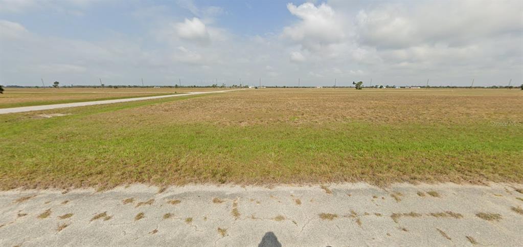 A wide, flat, grassy vacant lot is viewed from an adjacent paved road — 3 PENTAS WAY, PLACIDA, FL