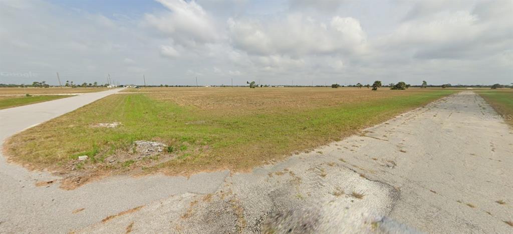 A vacant, grassy corner lot sits at the intersection of two paved roads — 3 PENTAS WAY, PLACIDA, FL