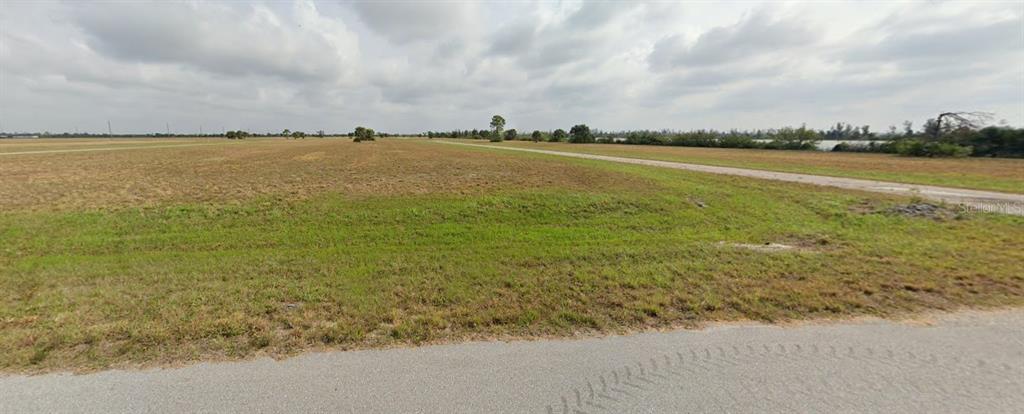 A wide, flat, grassy vacant lot under a cloudy sky next to a paved road — 3 PENTAS WAY, PLACIDA, FL