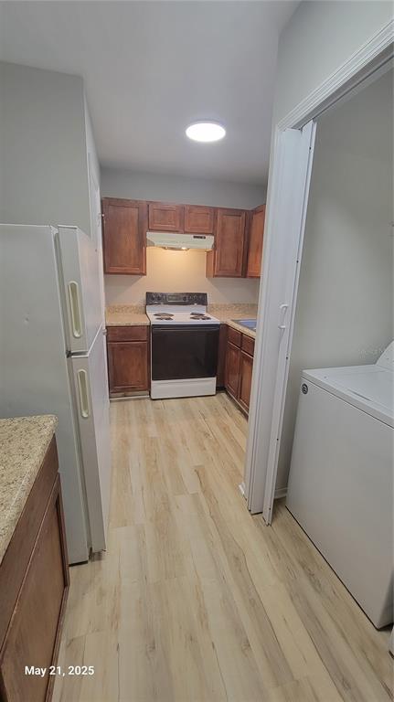 A kitchen features wood cabinets, a white stove, a refrigerator, and light-colored wood-look flooring — 4136 PERSHING POINTE PLACE UNIT 5, ORLANDO, FL