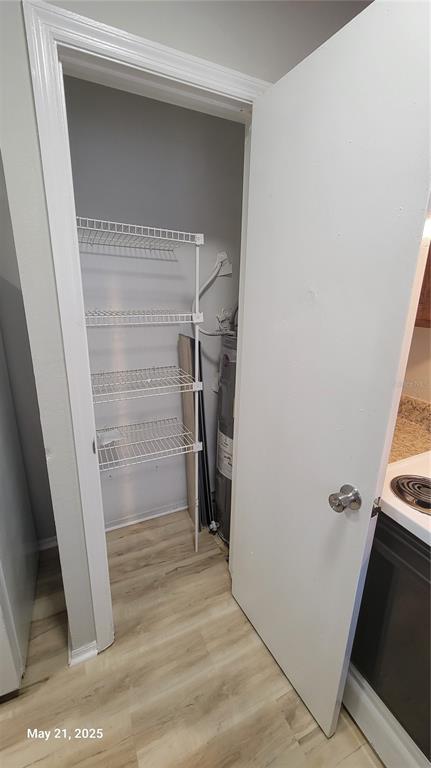 A utility closet contains wire shelving and a water heater next to a kitchen area — 4136 PERSHING POINTE PLACE UNIT 5, ORLANDO, FL