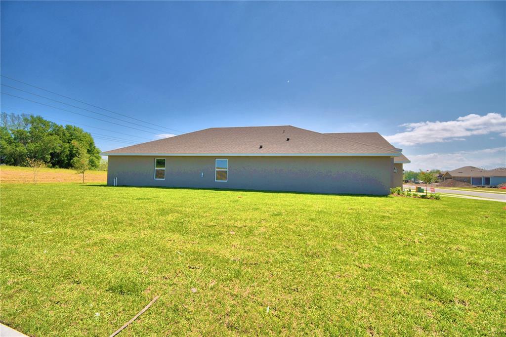 The exterior side view of a single-story house features a large lawn and two windows — 4632 CALAMINT LANE, AUBURNDALE, FL