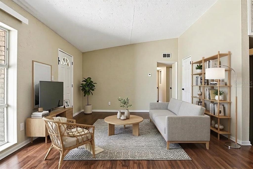 A living room with wood floors, a gray sofa, a round coffee table, and shelving — 5312 COVENTRY DRIVE, ORLANDO, FL