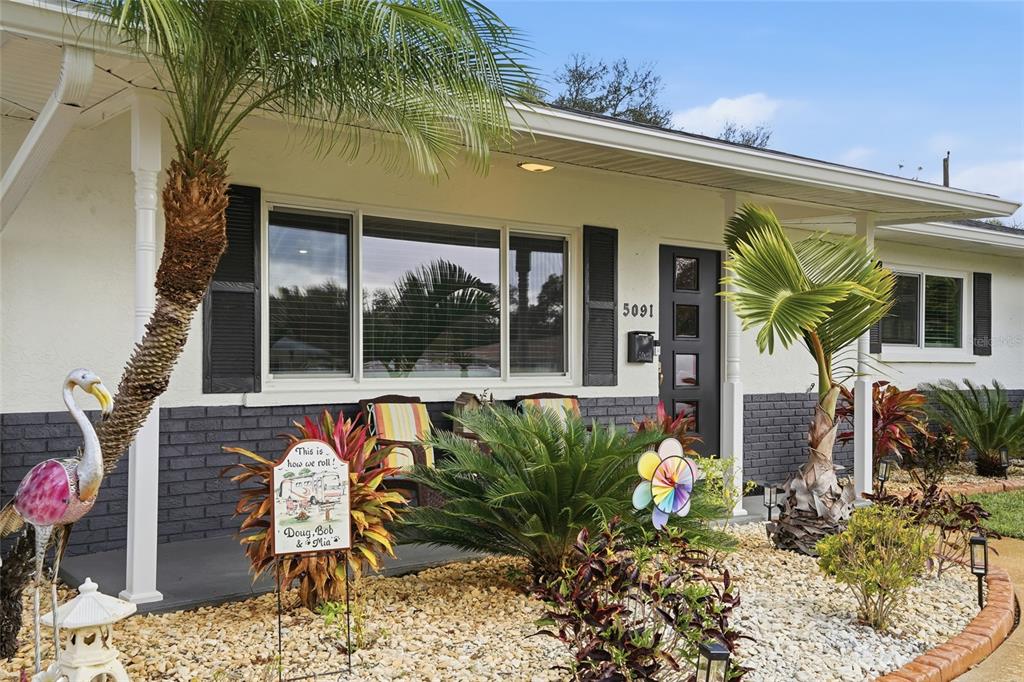 The exterior of a single-story house features a covered porch, palm trees, and landscaping — 5091 35TH TERRACE N, ST PETERSBURG, FL