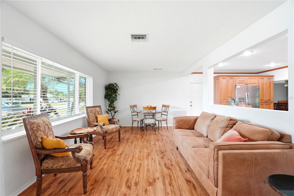 A living room features wood-look flooring, a brown sofa, two patterned armchairs, and a dining set — 5091 35TH TERRACE N, ST PETERSBURG, FL