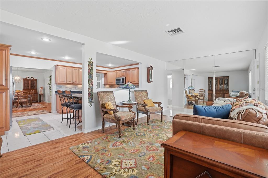 A living room with wood-look flooring, a patterned area rug, and an open kitchen view — 5091 35TH TERRACE N, ST PETERSBURG, FL
