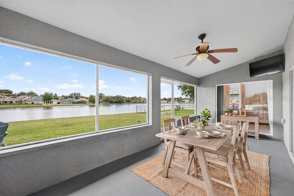 A grassy backyard features a fire pit, two chairs, and a view of a lake — 118 RACHEL LIN LANE, ST CLOUD, FL