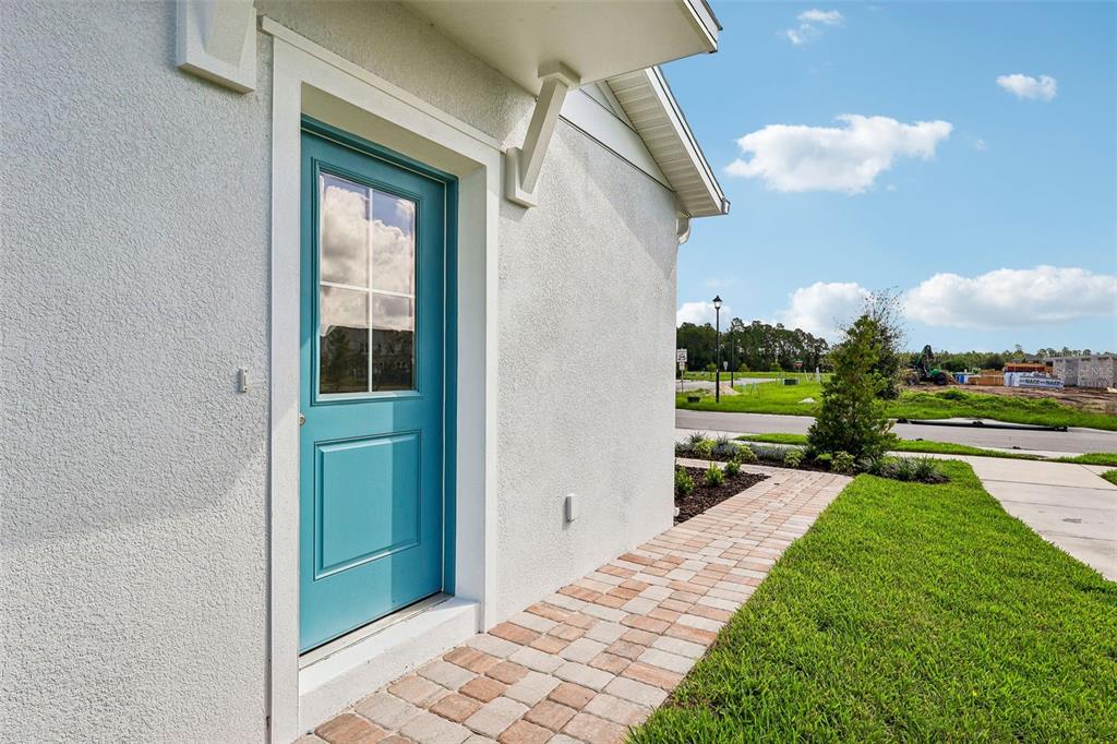 A teal door with a glass window sits on the side of a stucco house — 2712 MEADOW CREST DRIVE, ST CLOUD, FL