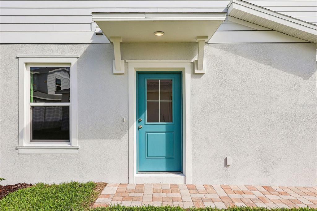 A teal door with a window sits under a small awning on a stucco house — 2712 MEADOW CREST DRIVE, ST CLOUD, FL