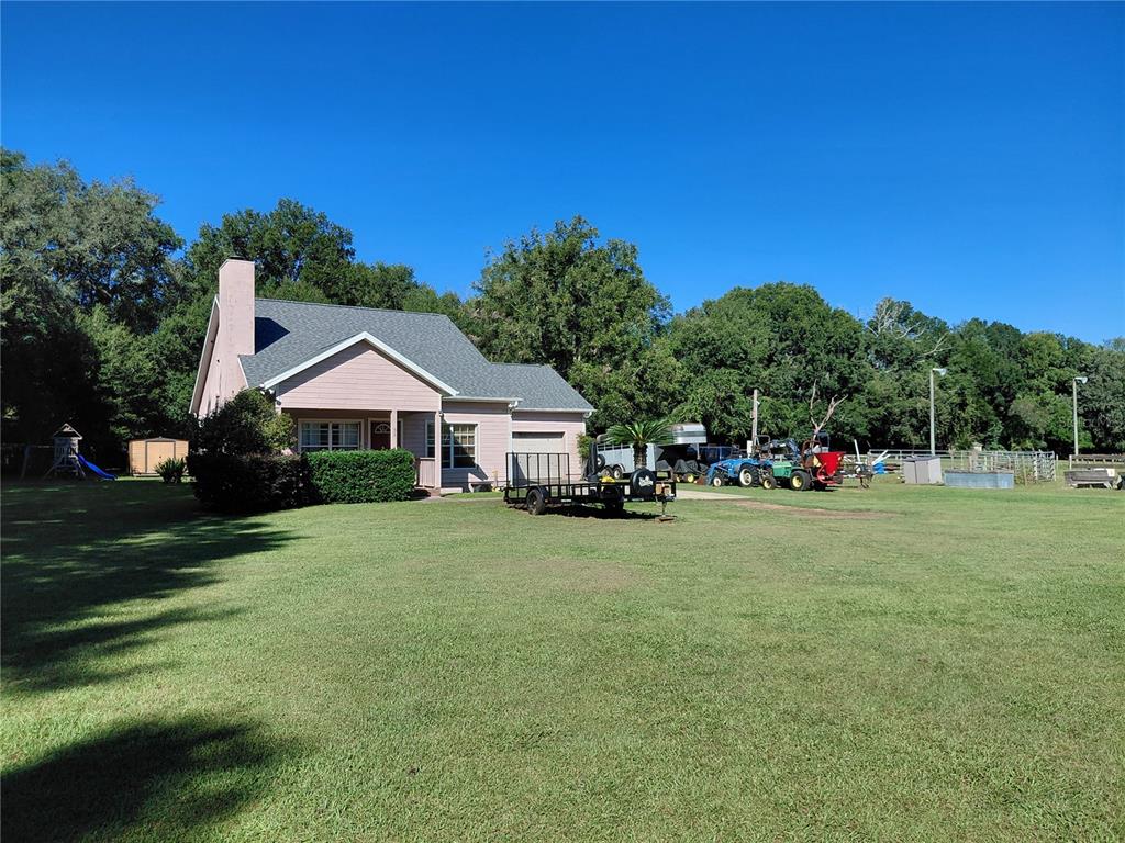 A pink house with a gray roof sits on a large, grassy lot with equipment — 33 PINE TRACE COURSE, OCALA, FL